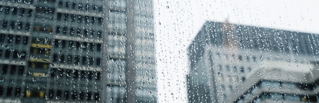 Rain covered window with tall office buildings in the background.